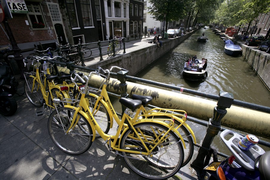 NETHERLANDS, AMSTERDAM, Yellow Bike rented bikes in front of the Keizersgracht ( Emperors Canal) with boats in Amsterdam.